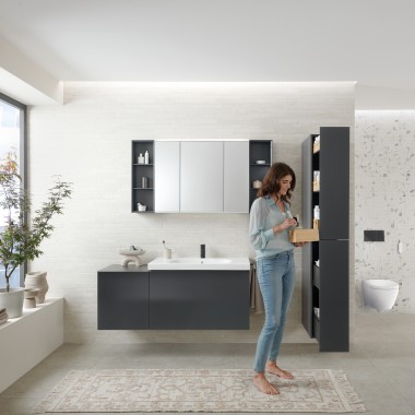 Woman opens tall cabinet with lots of storage space in bathroom with Geberit Acanto bathroom furniture