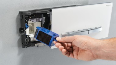 A man installs the Geberit DuoFresh module in a wall-mounted actuator plate (© Geberit)