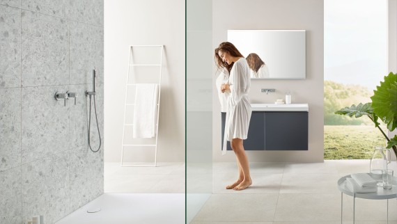 Woman in bathroom with walk-in shower and Geberit Olona shower surface